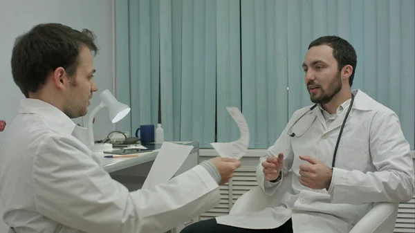 Male doctor and young intern in a good mood talking about new medical researchs — Stock Photo, Image