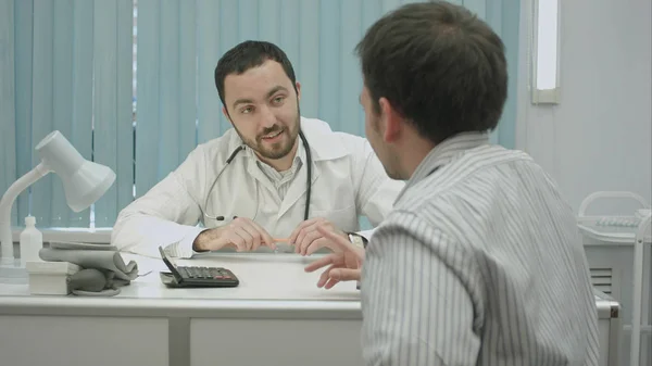 Mannelijke bebaarde doctor in de kliniek bieden goede prijs voor behandeling. — Stockfoto
