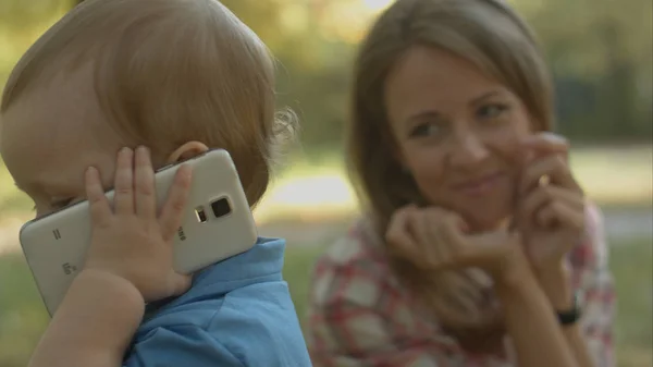 Мама смотрит, как маленький сын звонит отцу по телефону. . — стоковое фото