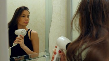 Genç çekici kız bir otel banyoda bir saç kurutma makinesi ile saç kurur