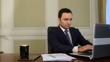 ofiste dizüstü bilgisayar üzerinde çalışan iş adamı