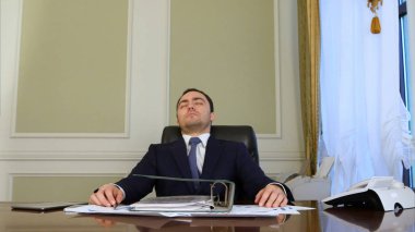 Overworked businessman falling asleep in office clipart
