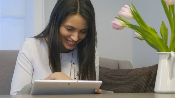 Una donna attraente usa il suo nuovo tablet digitale nel suo salotto — Foto Stock