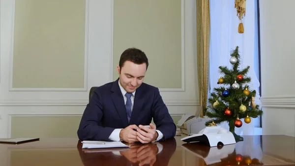 Красивий бізнесмен пише SMS-повідомлення своїй милій дружині, використовуючи мобільний телефон перед Різдвом — стокове фото