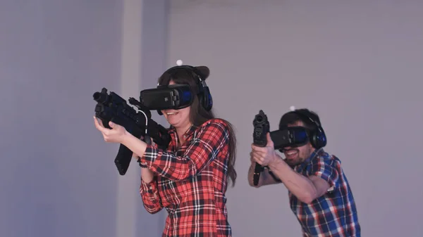 Friends playing VR shooter game with virtual reality guns and glasses