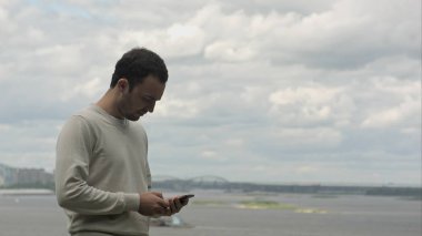 Nehri yakınında cep telefonuyla konuşurken gülümseyen iş adamı