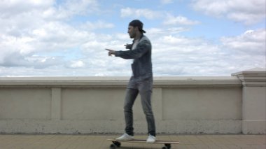 Şehrin sokak üzerinde kaykay sürme genç gülen adam.