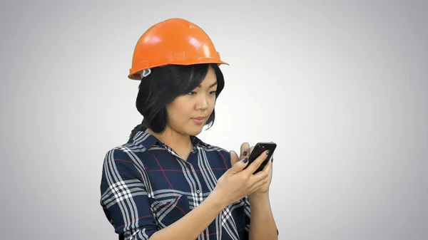 Arsitek wanita dengan helm oranye menggunakan smartphone dengan latar belakang putih — Stok Foto