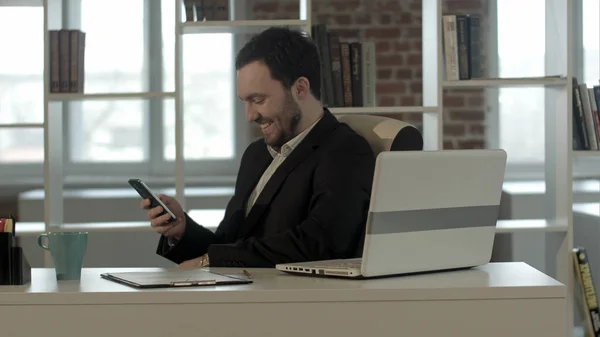 Gente feliz con hombre de negocios en el teléfono escribiendo mensaje de texto en la oficina — Foto de Stock