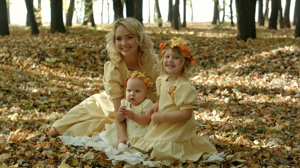 Beautiful young woman with maple leaves sitting with her baby