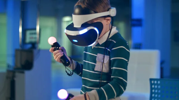 Niño pequeño con auriculares de realidad virtual sosteniendo los controladores de movimiento —  Fotos de Stock
