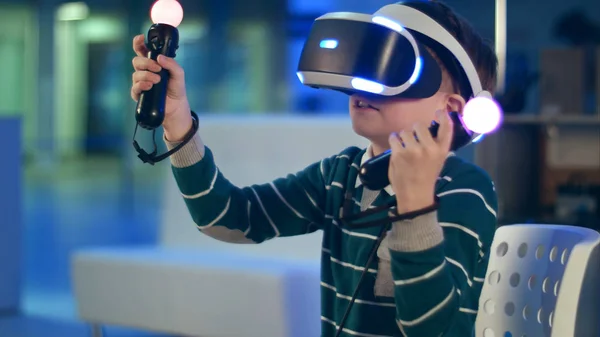 Niño activo disfrutando de la realidad virtual con controladores de movimiento en sus manos —  Fotos de Stock