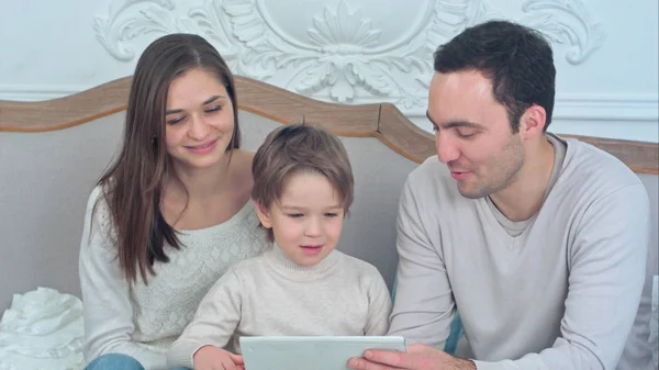 Счастливая семья и сын смотрят планшет на диване — стоковое фото