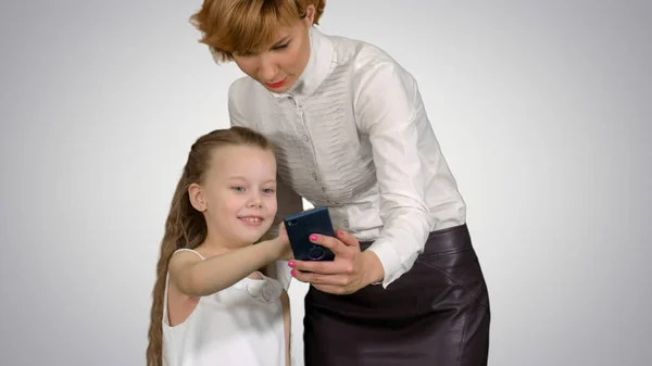 Молода мама навчає доньку, як користуватися смартфоном на білому тлі — стокове фото