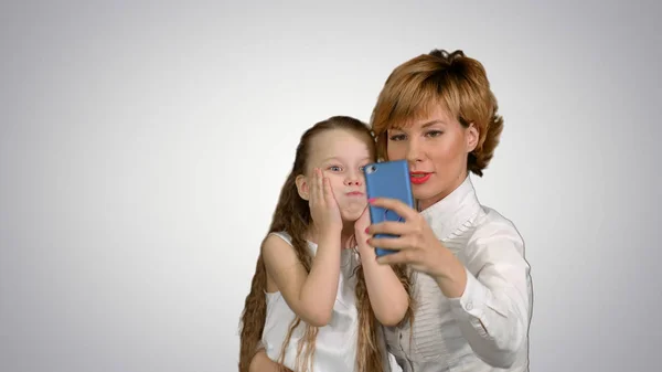 Милая мать семьи с ребенком дочь делает селфи смартфон фото на белом фоне — стоковое фото