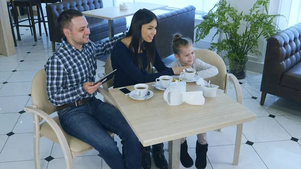 Дружная семья, сидящая в кафе, улыбающаяся, позирующая и извиняющаяся . — стоковое фото