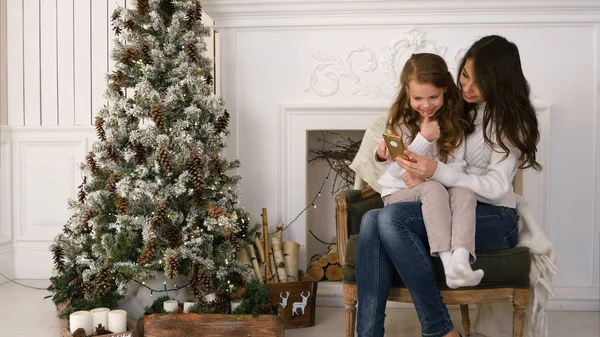 Happy mother and daughter taking funny Christmas selfies at home