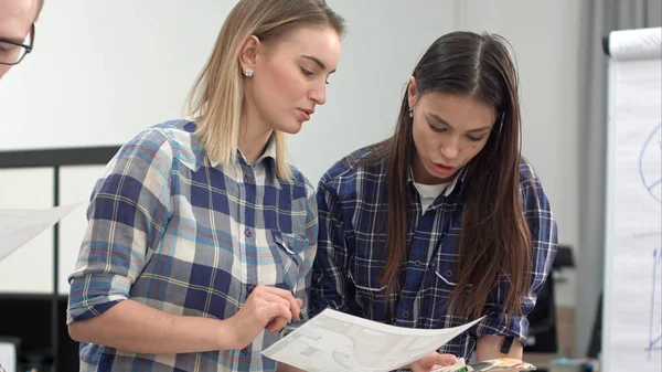 Две женщины-дизайнера обсуждают макет и цветные образцы — стоковое фото