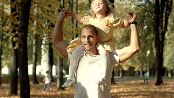 Little girl in the arms of his father walk in autumn park