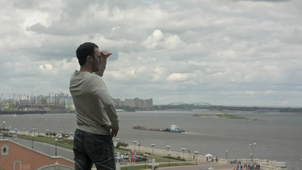 Guapo joven de pie cerca del río y mirando hacia adelante . — Foto de Stock