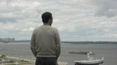 Genç bir işadamı nehir kenarında duran, dört gözle ve düşünme.