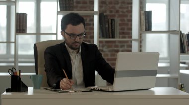 üstünde onun defter, taze bir fincan kahve güzel ve sabah erken ile çalışma komik gözlüklü genç adam yoldan güzel ve erken bir saat iş Başlarken