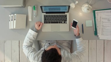 Doktor, ofisinde telefonda mutlu bir konuşma yapıyor. Üst görünüm