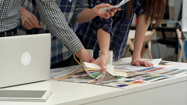 Jóvenes diseñadores trabajando con paleta de colores y muestras en el escritorio de la oficina — Foto de Stock