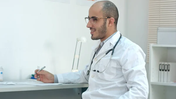 Médico masculino positivo no consultório conversando com o paciente — Fotografia de Stock