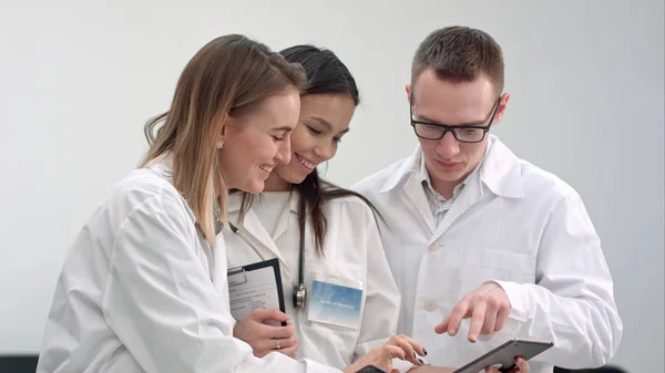 Tři usmívající se lékaři diskutovat rentgenové při používání tabletu — Stock fotografie