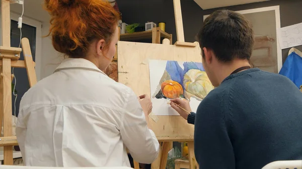 Professor de arte feminino explicando estudante como aplicar aquarelas — Fotografia de Stock
