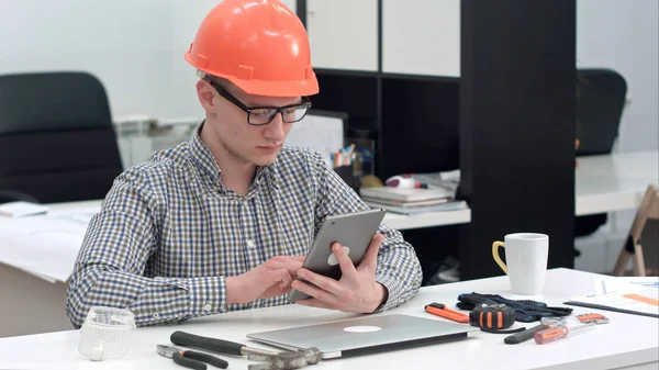 Arquiteto com capacete de segurança usando tablet eletrônico no escritório — Fotografia de Stock