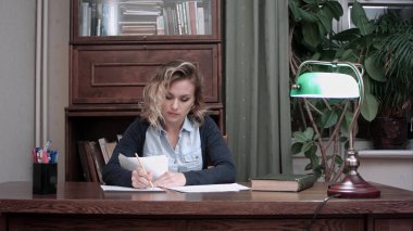 Genç kadının evrak masasında oturan ofiste yapması