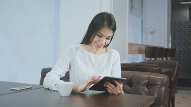 Mutlu genç kadın bir kafede dijital tablet kullanma