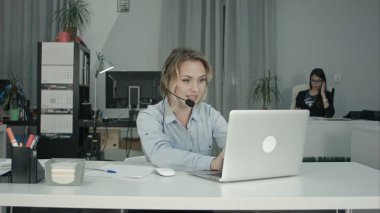 Gülümseyen çağrı merkezi operatörü kulaklık kullanma office dizüstü bilgisayar ile çalışma