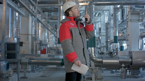 Engineer working in a thermal power plant with talking on the walkie-talkie for controlling work