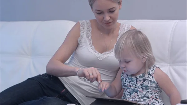 Madre enseñando a su bebé cómo usar la tableta — Foto de Stock