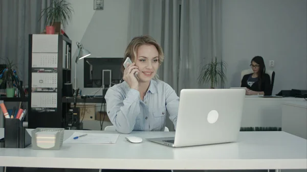 Две сотрудницы, работающие вместе, отвечают на телефонные звонки в офисе — стоковое фото