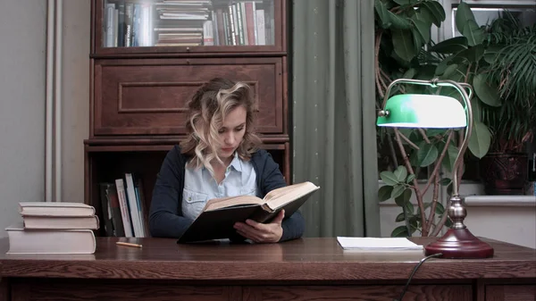 Onun masasında genç ve güzel kadın oturma ve iş raporu için kitapta araştırma