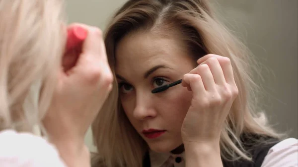 Schoonheid tienermeisje toepassing van mascara en het bewonderen van zichzelf in de spiegel — Stockfoto