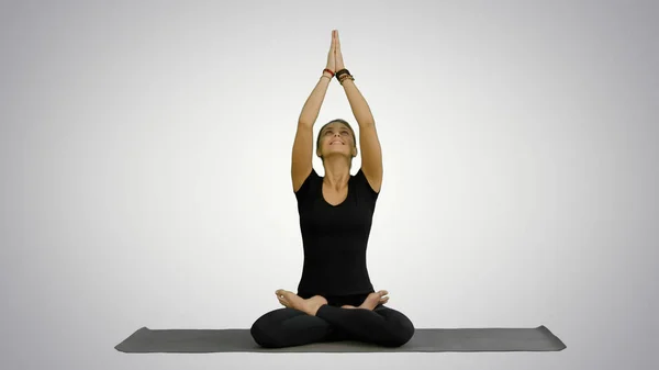 Jovem praticando ioga, sentada em uma posição de lótus, meditando com os olhos fechados no fundo branco — Fotografia de Stock