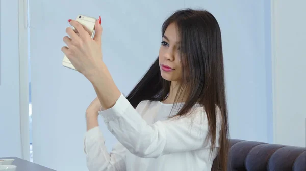 Chica bastante joven cepillándose el pelo usando el teléfono como espejo — Foto de Stock