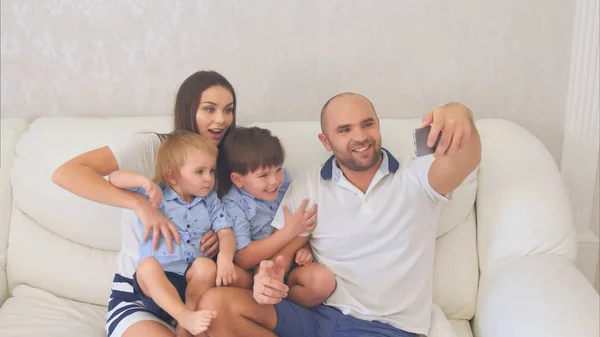 Sonriente familia tomando divertidos selfies sentado en el sofá —  Fotos de Stock