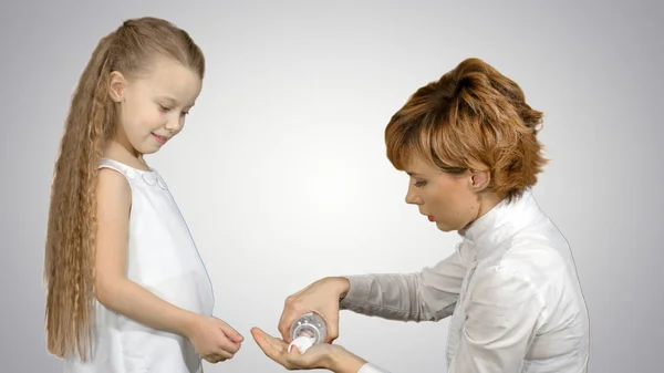 Moeder geeft haar dochter geneeskunde op witte achtergrond — Stockfoto