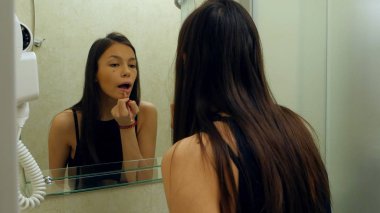 Evde banyoda ruj uygulayarak güzel, zarif kadın