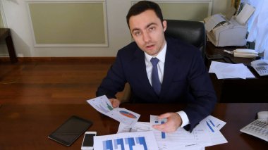 Kendine güvenen işadamı yatırım grafikler ve kameraya bakarak istatistik analiz
