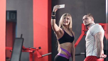 Atletik çift spor salonunda telefonda selfie 'ler alıyor
