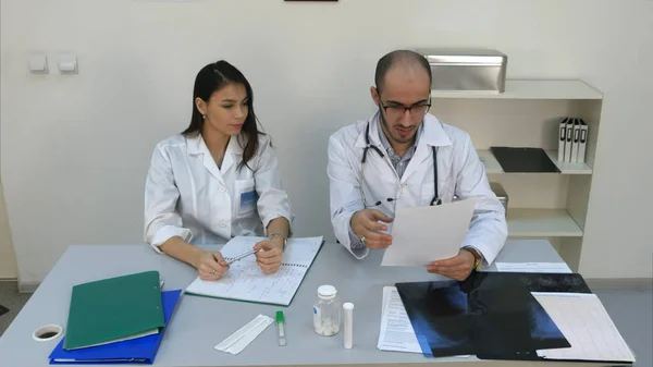 Dottore mostrando la sua assistente femminile come leggere il cardiogramma mentre lei prende appunti — Foto Stock