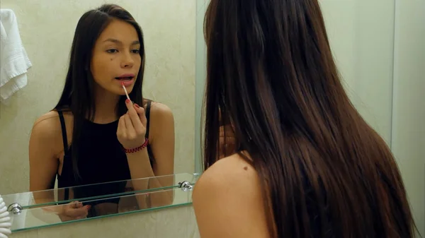 Retrato de una chica joven y atractiva rugiendo sus labios y sonriendo a su reflejo — Foto de Stock