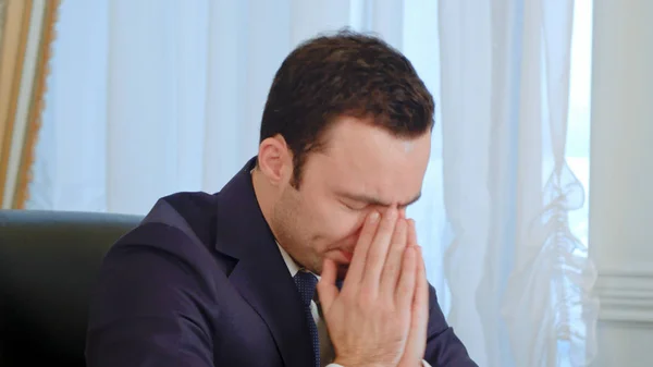 Sick young businessman coughing and blowing his nose in office — Stock Photo, Image